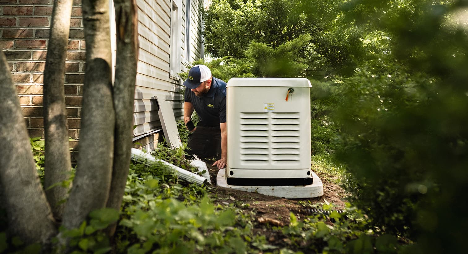 A professional Maitz technician inspects a large, beige whole-home standby generator installed on a concrete pad outside a residential house.