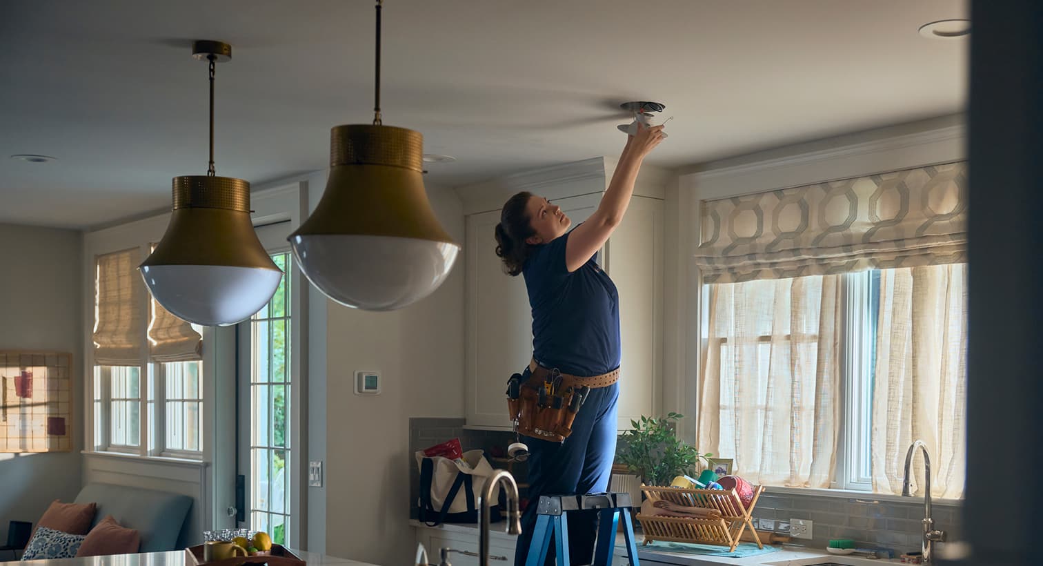 A professional Maitz electrician standing on a ladder to install modern recessed ceiling lights during a residential electrical installation service.